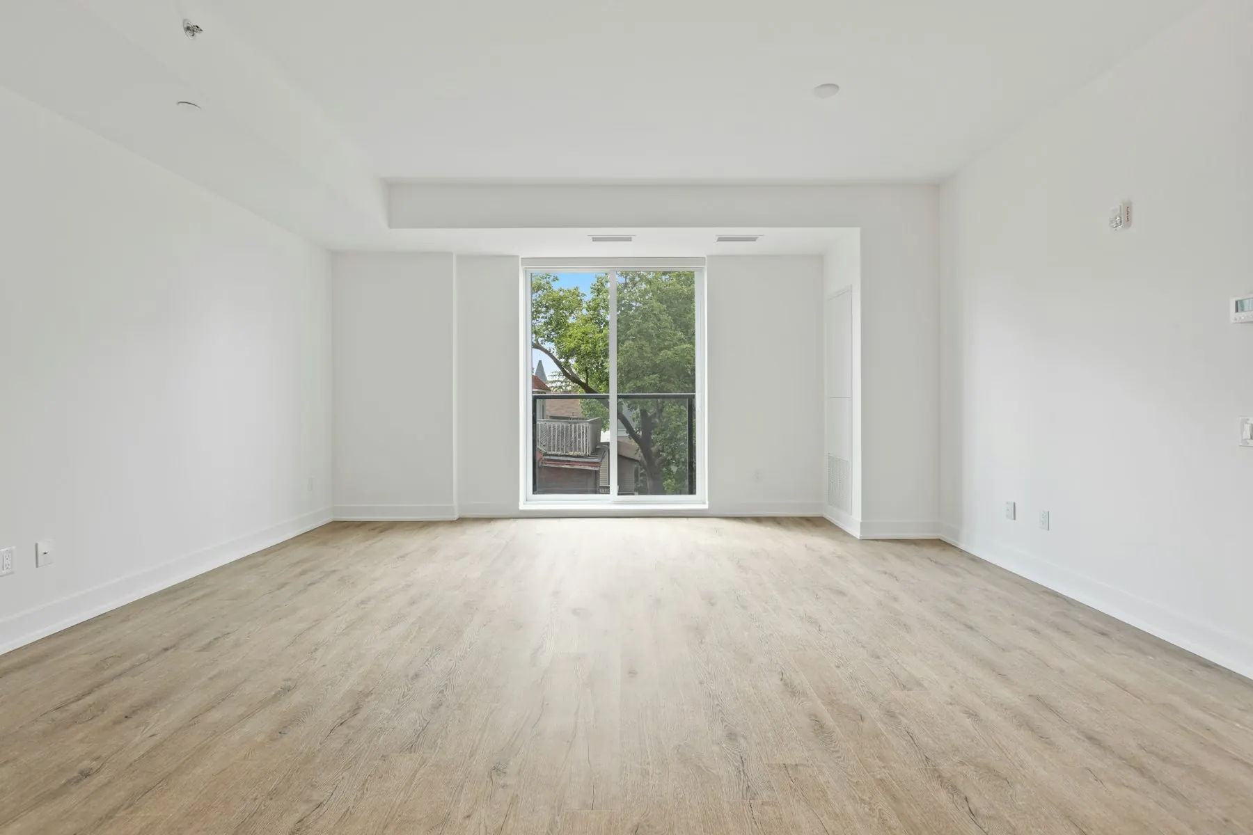 Heller, leerer Raum mit Holzboden und bodentiefem Fenster (Beispielbild)